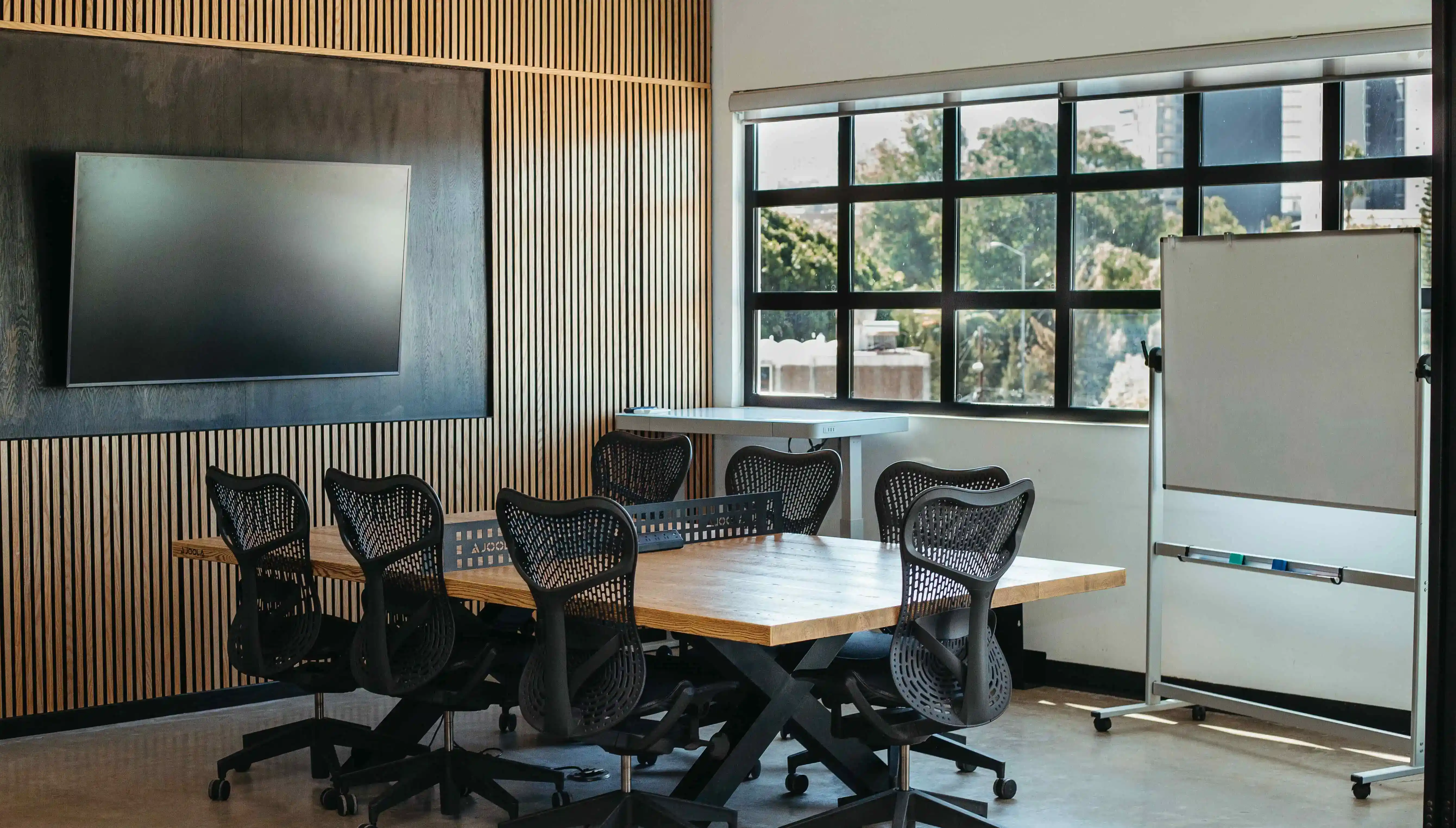 Foto de una sala de conferencias con una mesa rectangular, sillas y un televisor.